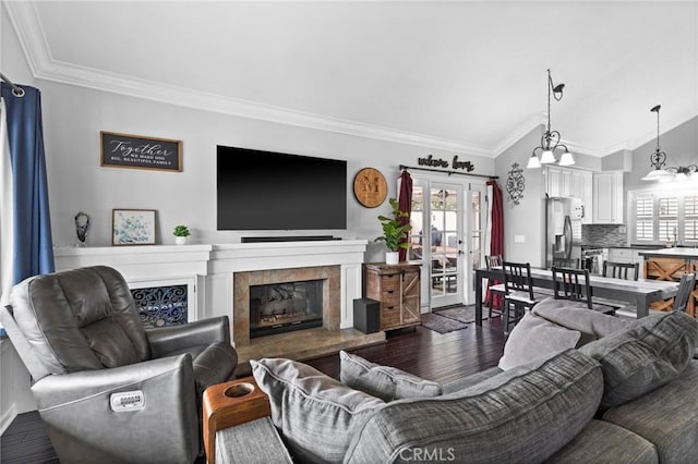 living area featuring a tile fireplace, wood finished floors, french doors, crown molding, and vaulted ceiling