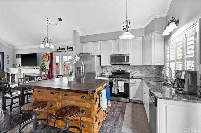 kitchen with a sink, dark wood-style floors, white cabinetry, stainless steel appliances, and decorative backsplash