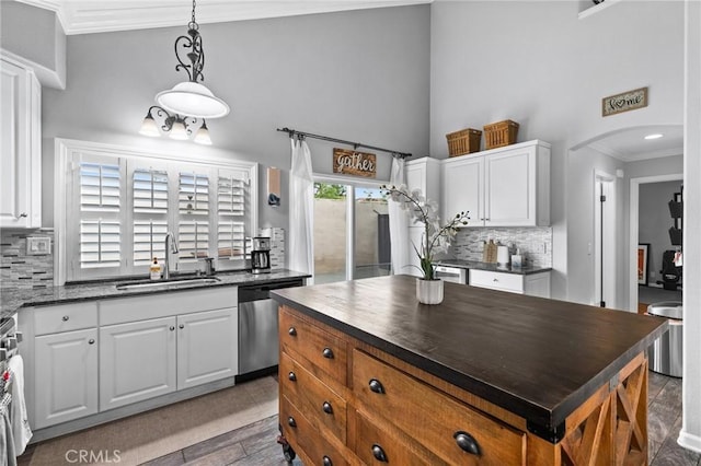 kitchen featuring a sink, stainless steel appliances, arched walkways, and white cabinets