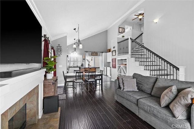 living area with a high end fireplace, crown molding, dark wood-type flooring, stairway, and high vaulted ceiling