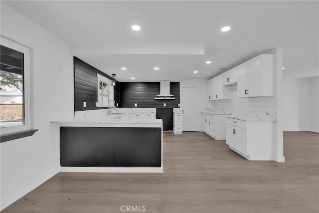 kitchen featuring white cabinets, a sink, light wood-style flooring, and exhaust hood