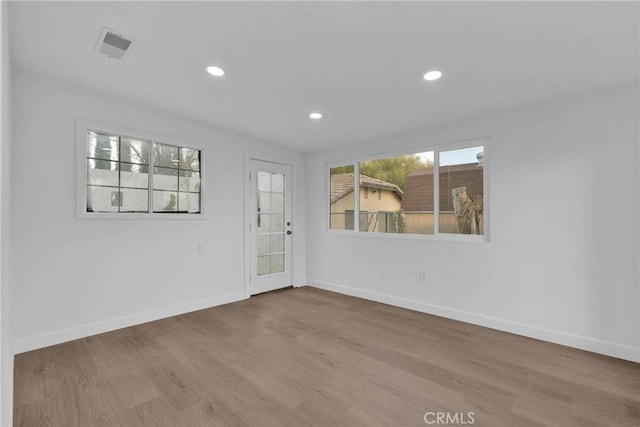 empty room featuring recessed lighting, visible vents, baseboards, and wood finished floors