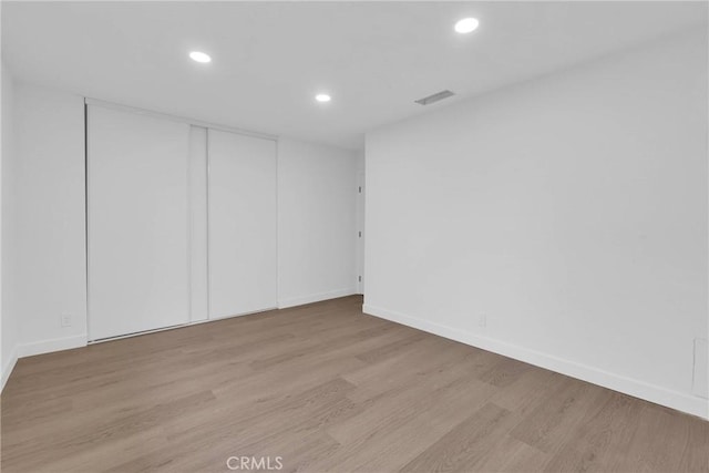 unfurnished room featuring baseboards, visible vents, wood finished floors, and recessed lighting