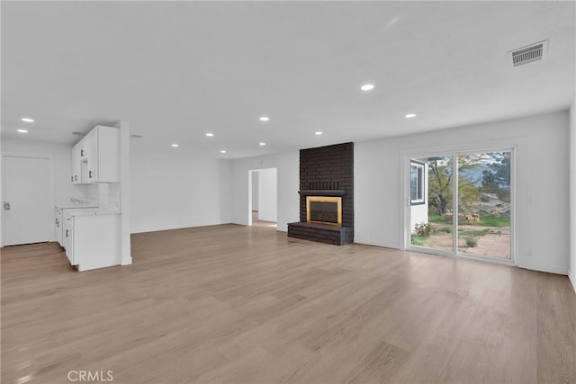 unfurnished living room with recessed lighting, a fireplace, visible vents, and light wood-style floors