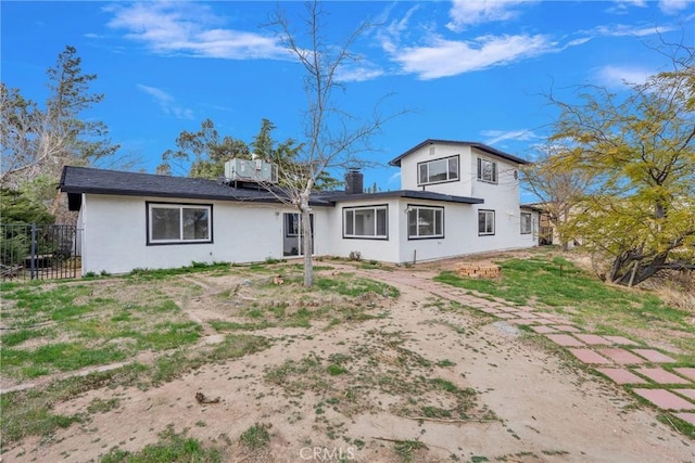 rear view of house featuring fence and stucco siding