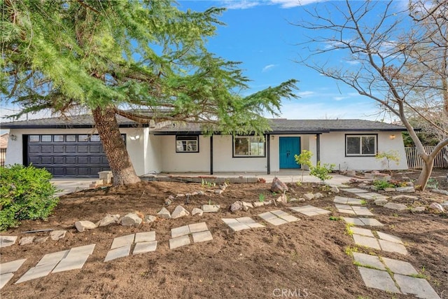 ranch-style house featuring an attached garage, fence, and stucco siding