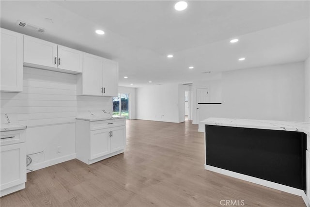 kitchen featuring recessed lighting, white cabinets, light wood-style flooring, and light stone countertops