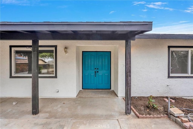 doorway to property featuring stucco siding