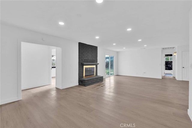 unfurnished living room featuring light wood finished floors, a fireplace, baseboards, and recessed lighting