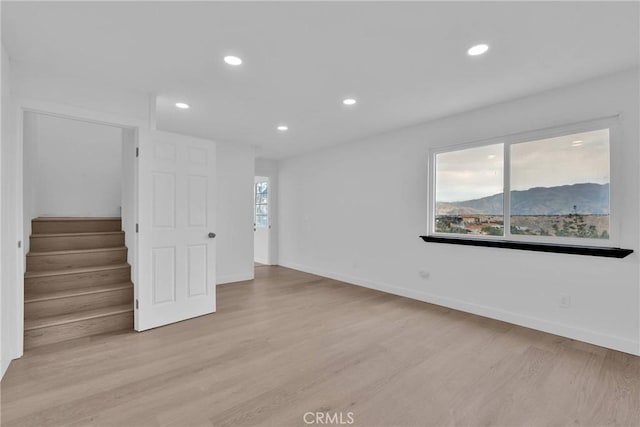 unfurnished room with light wood-type flooring, baseboards, recessed lighting, and stairs