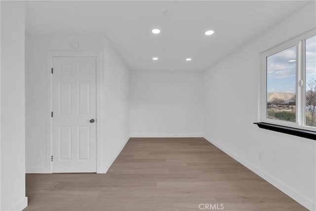 empty room with light wood finished floors, baseboards, and recessed lighting