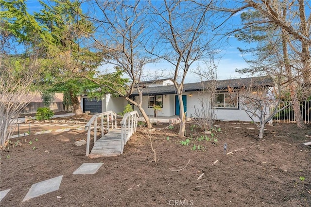 view of front of home featuring a garage, fence, and stucco siding