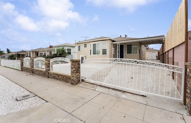 view of front facade with a fenced front yard, a gate, and stucco siding