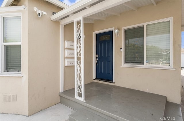 doorway to property with an attached garage and stucco siding