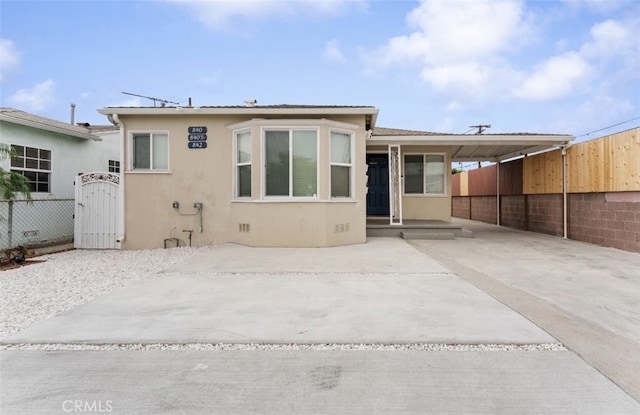 back of property with an attached carport, fence, concrete driveway, crawl space, and stucco siding