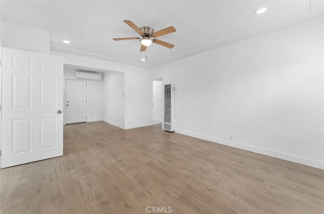 unfurnished room featuring ceiling fan, recessed lighting, baseboards, light wood-style floors, and a wall mounted air conditioner