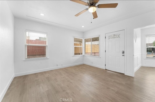 unfurnished room with a ceiling fan, light wood-style flooring, and baseboards