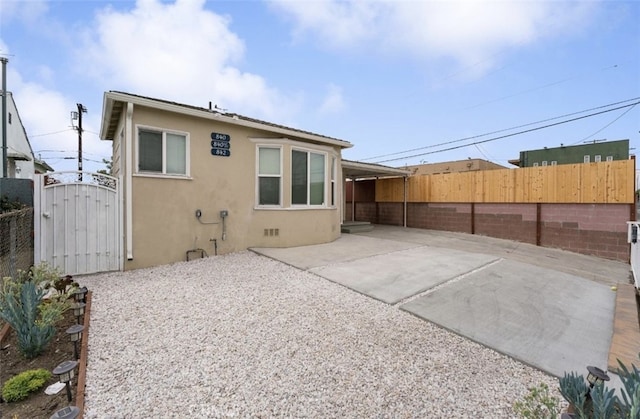 rear view of property featuring a patio, stucco siding, a gate, crawl space, and fence