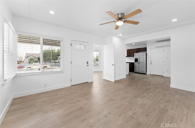 unfurnished living room with a wall unit AC, light wood finished floors, recessed lighting, ceiling fan, and baseboards