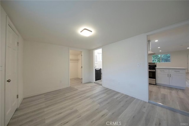 spare room featuring light wood finished floors, recessed lighting, and baseboards