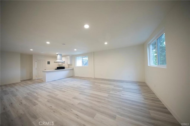 unfurnished living room with baseboards, recessed lighting, and light wood-style floors