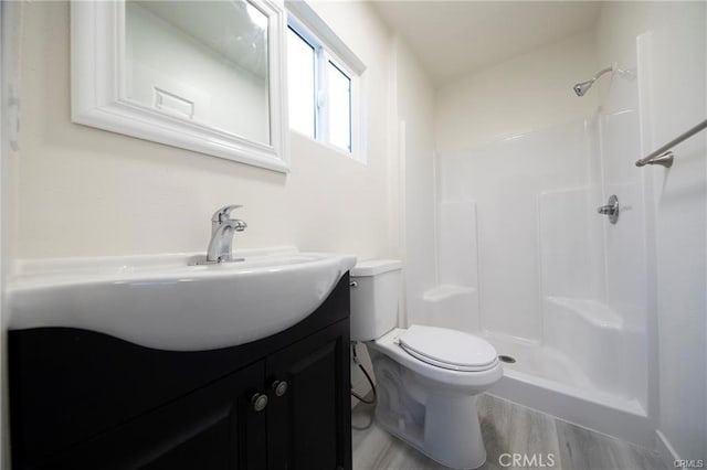 bathroom featuring toilet, walk in shower, wood finished floors, and vanity