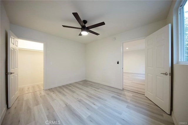 unfurnished bedroom with baseboards, multiple windows, a ceiling fan, and light wood-style floors