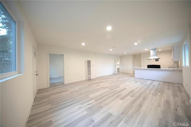 unfurnished living room with recessed lighting, a fireplace, a sink, and light wood finished floors