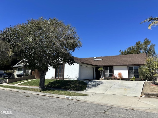 view of front of property featuring a garage, concrete driveway, a front yard, and stucco siding