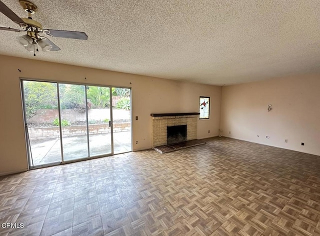 unfurnished living room featuring baseboards, a brick fireplace, a textured ceiling, and a ceiling fan