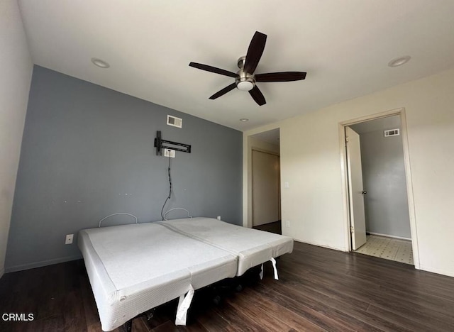 bedroom featuring a ceiling fan, wood finished floors, visible vents, and baseboards