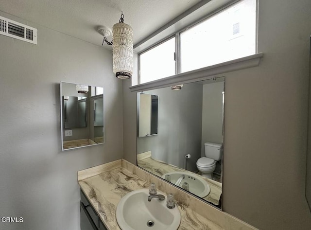 bathroom featuring vanity, toilet, and visible vents