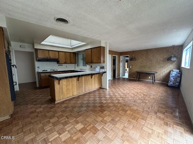 kitchen with a peninsula, gas stovetop, visible vents, and a textured ceiling