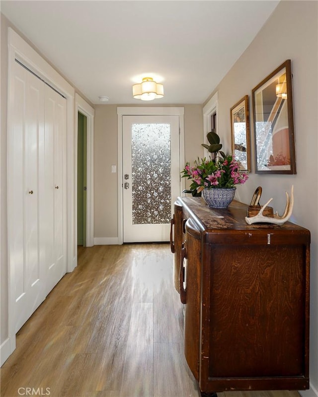 doorway to outside featuring light wood-style flooring and baseboards