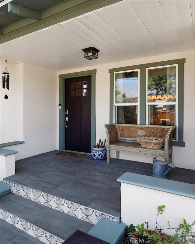 view of exterior entry featuring a porch and stucco siding