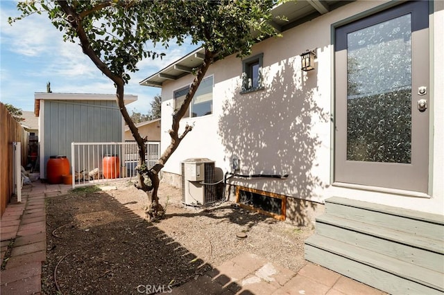 exterior space with cooling unit, fence, and stucco siding