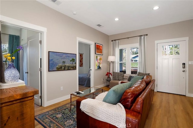 living area with baseboards, light wood-style flooring, visible vents, and recessed lighting