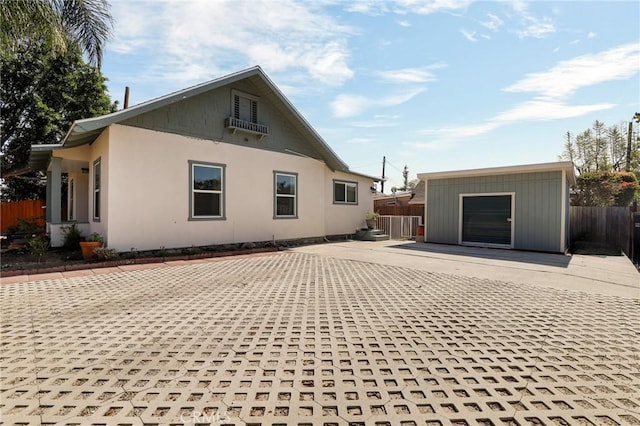 view of side of property featuring a patio area, fence, and an outbuilding