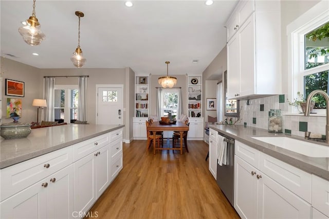 kitchen with a healthy amount of sunlight, a sink, light wood-style flooring, and stainless steel dishwasher