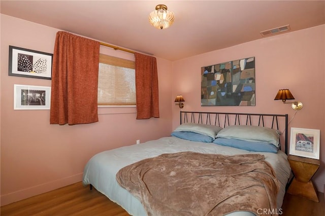 bedroom with visible vents, baseboards, and wood finished floors