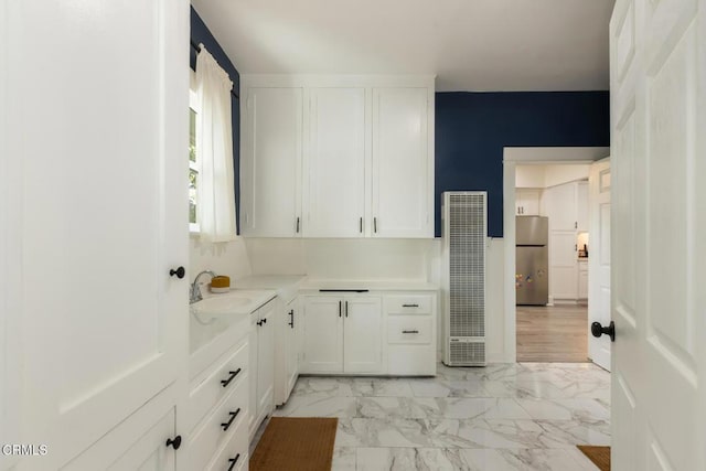 kitchen with freestanding refrigerator, marble finish floor, light countertops, and white cabinets