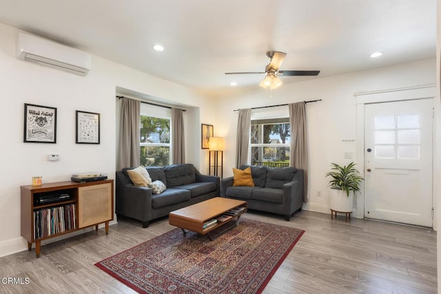 living room featuring recessed lighting, a wall unit AC, wood finished floors, and baseboards