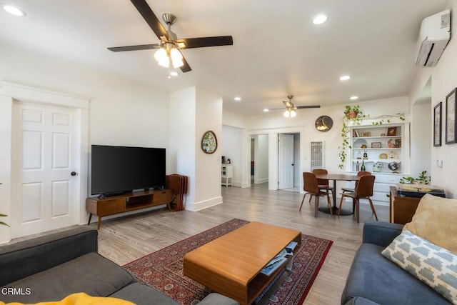 living room featuring ceiling fan, a wall unit AC, recessed lighting, wood finished floors, and baseboards