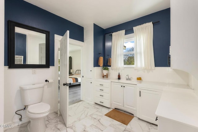 ensuite bathroom featuring marble finish floor, vanity, toilet, and ensuite bathroom