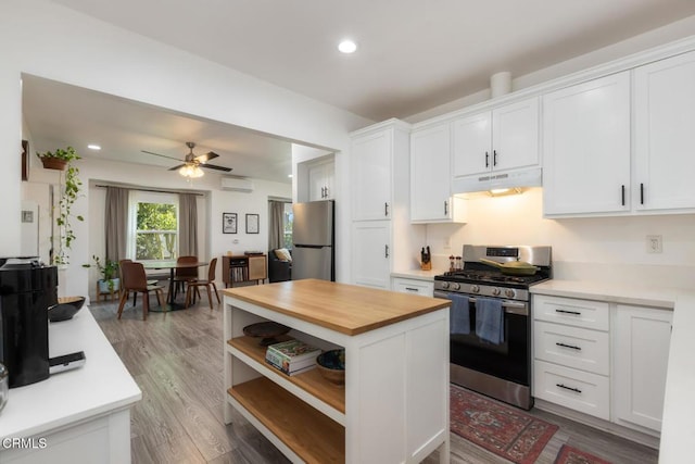 kitchen featuring appliances with stainless steel finishes, butcher block counters, white cabinets, and under cabinet range hood