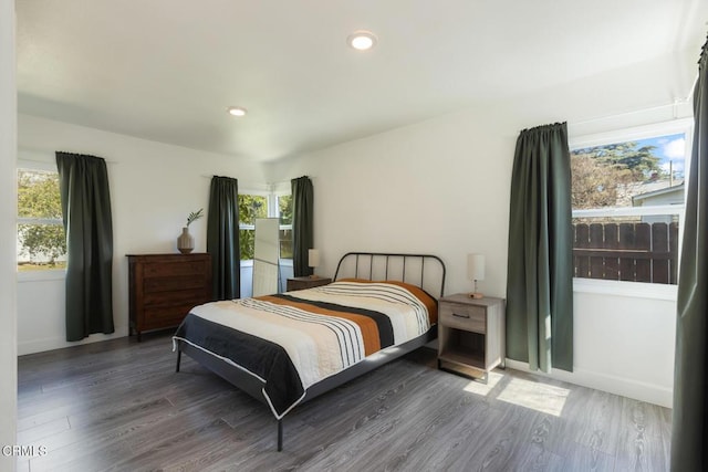 bedroom with recessed lighting, multiple windows, baseboards, and wood finished floors