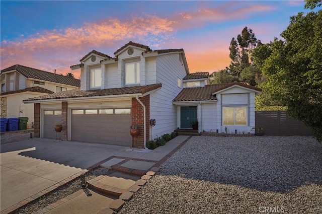 traditional-style home with an attached garage, brick siding, a tile roof, fence, and driveway