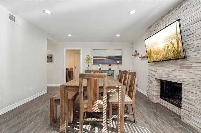 dining area featuring baseboards, a fireplace, visible vents, and wood finished floors