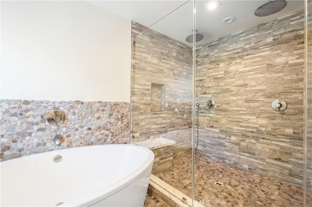 bathroom with tiled shower, a freestanding tub, and tile walls