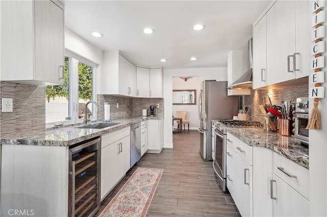 kitchen featuring dark wood finished floors, stainless steel appliances, white cabinetry, a sink, and beverage cooler